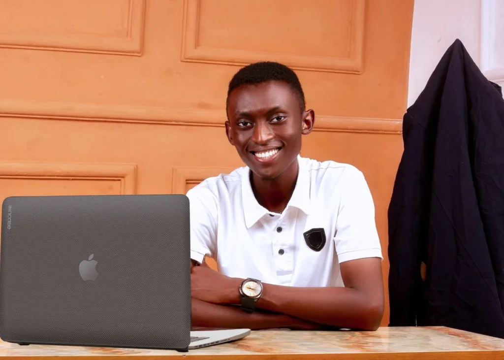 Young African man smiling at a desk with a laptop in an office